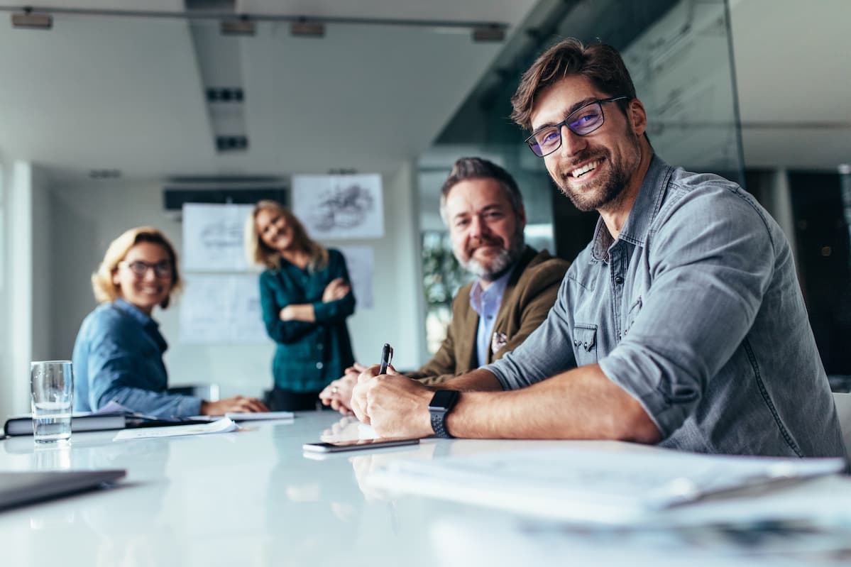 stock-photo-happy-group-of-businesspeople-during-presentation-colleagues-looking-at-camera-and-smiling-755621713 photo d’une équipe souriante et chaleureuse